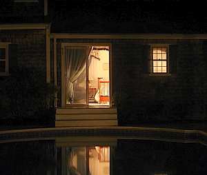 A view of Sweet 6 at night from the far side of the pool with light reflecting on the water