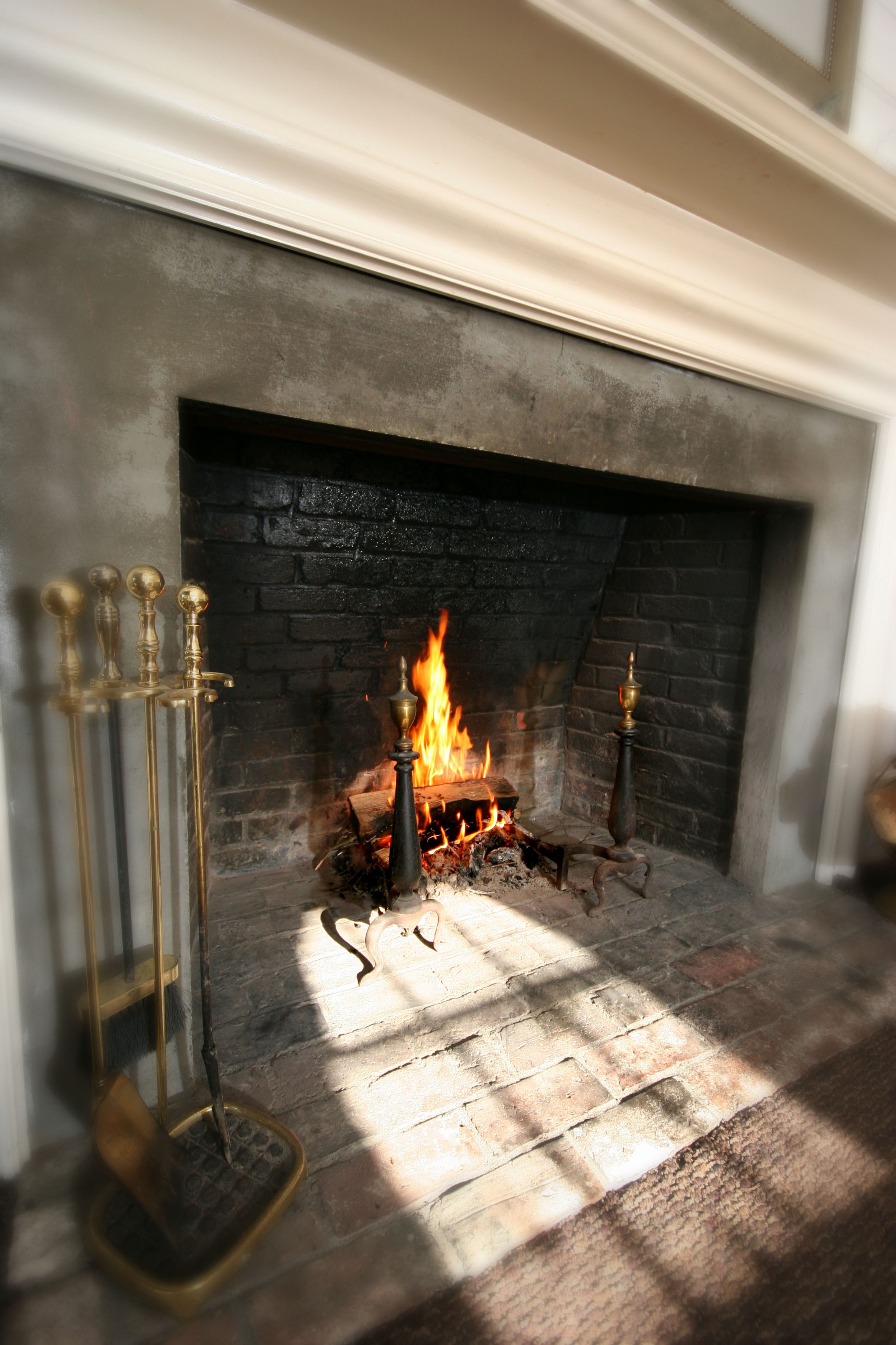 A roaring wood-burning fire with sunlight reflecting onto the fireplace