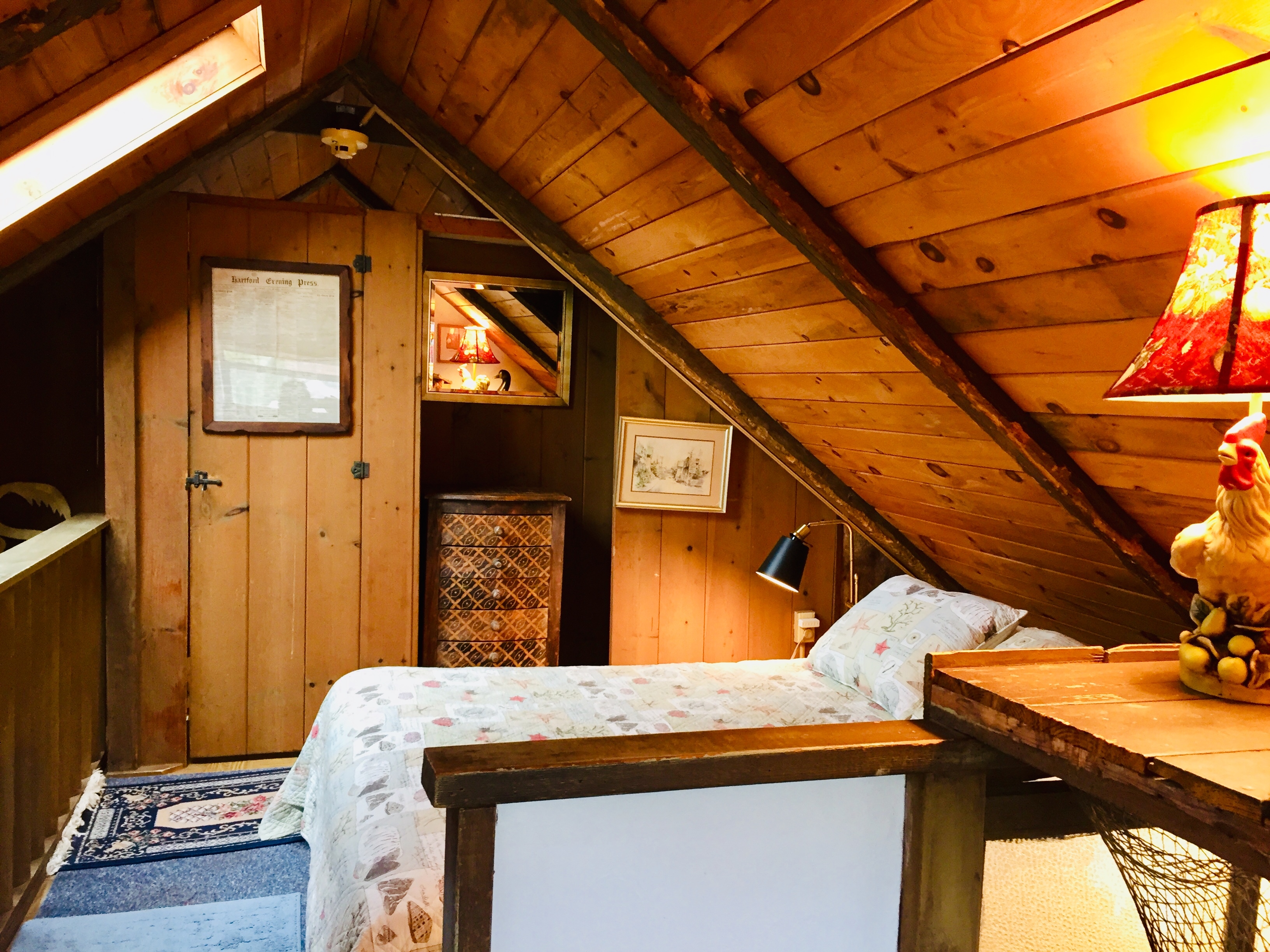 Photo of a loft bedroom with a slanted ceiling and light entering from a sky light.