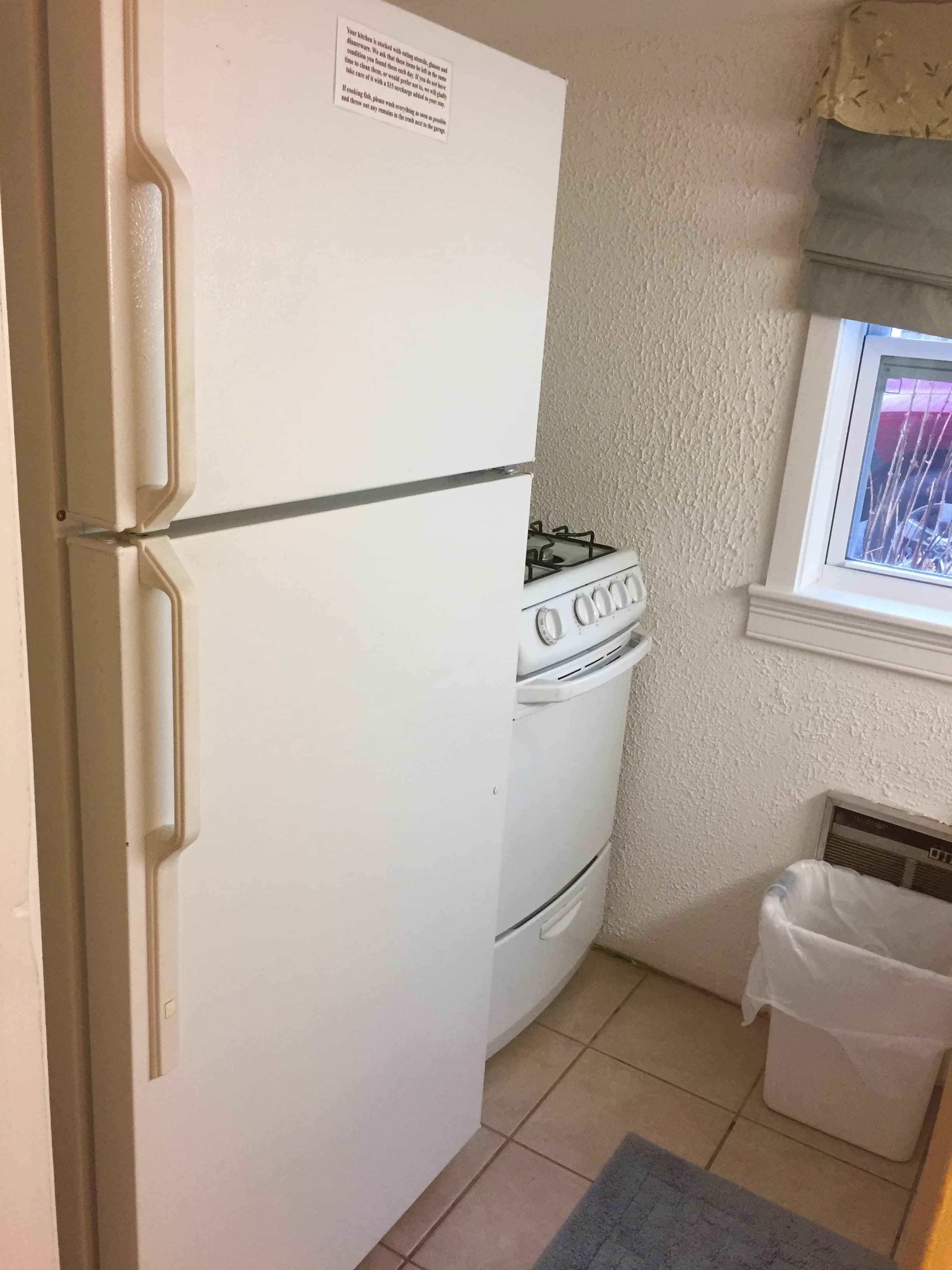 A white refrigerator and freezer in the kitchen with stove and window