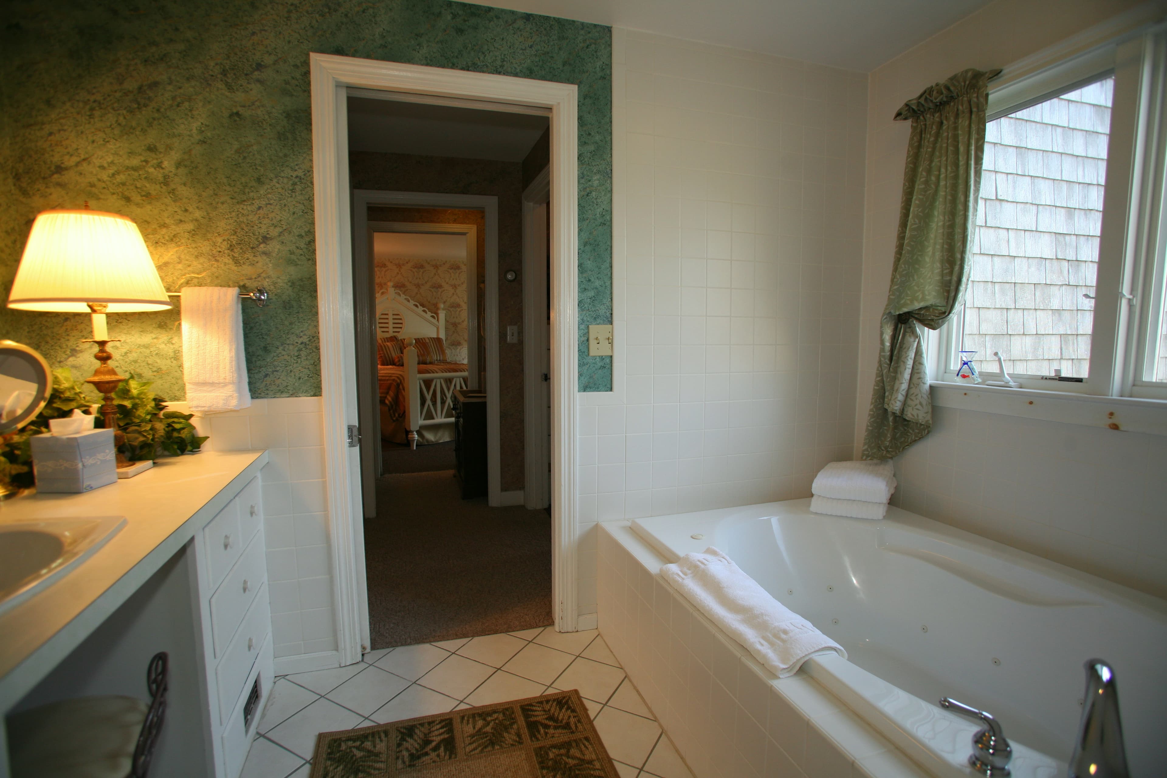 Partial photo of Innkeeper's Pride bathroom Jacuzzi. There is a lamp on and green wallpaper