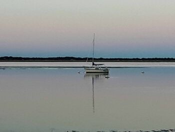 A sail boat is anchored at sunset