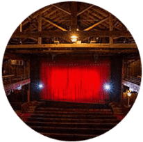 The playhouse has a red curtain closed with plenty of open seating