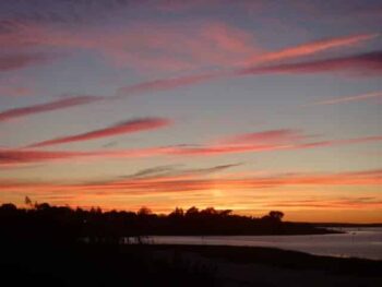 Photo of sunrise or sunset with pink clouds and body of water